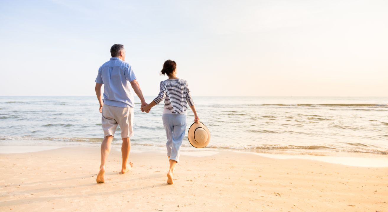 A couple is walking hand in hand at the beach