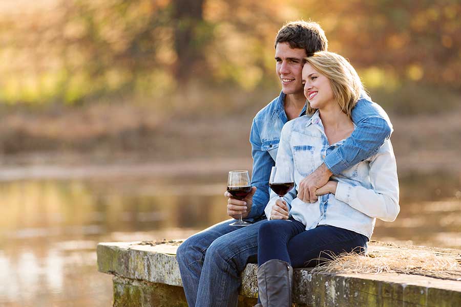 Couple sitting on dock drinking red wine