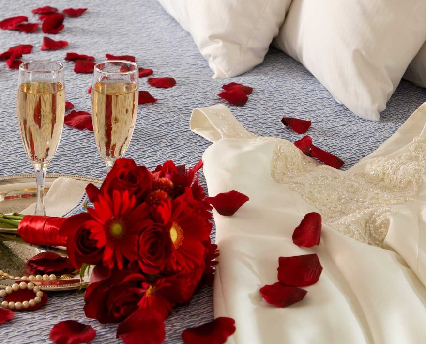Champagne, bouquet of red flowers and wedding dress