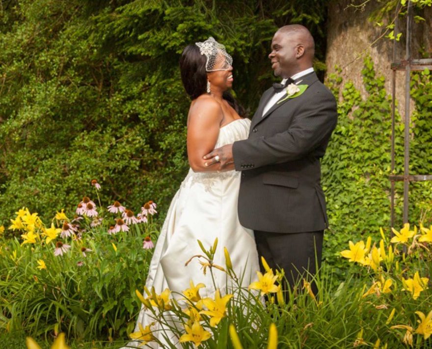 Bride and groom standing in garden of yellow flowers