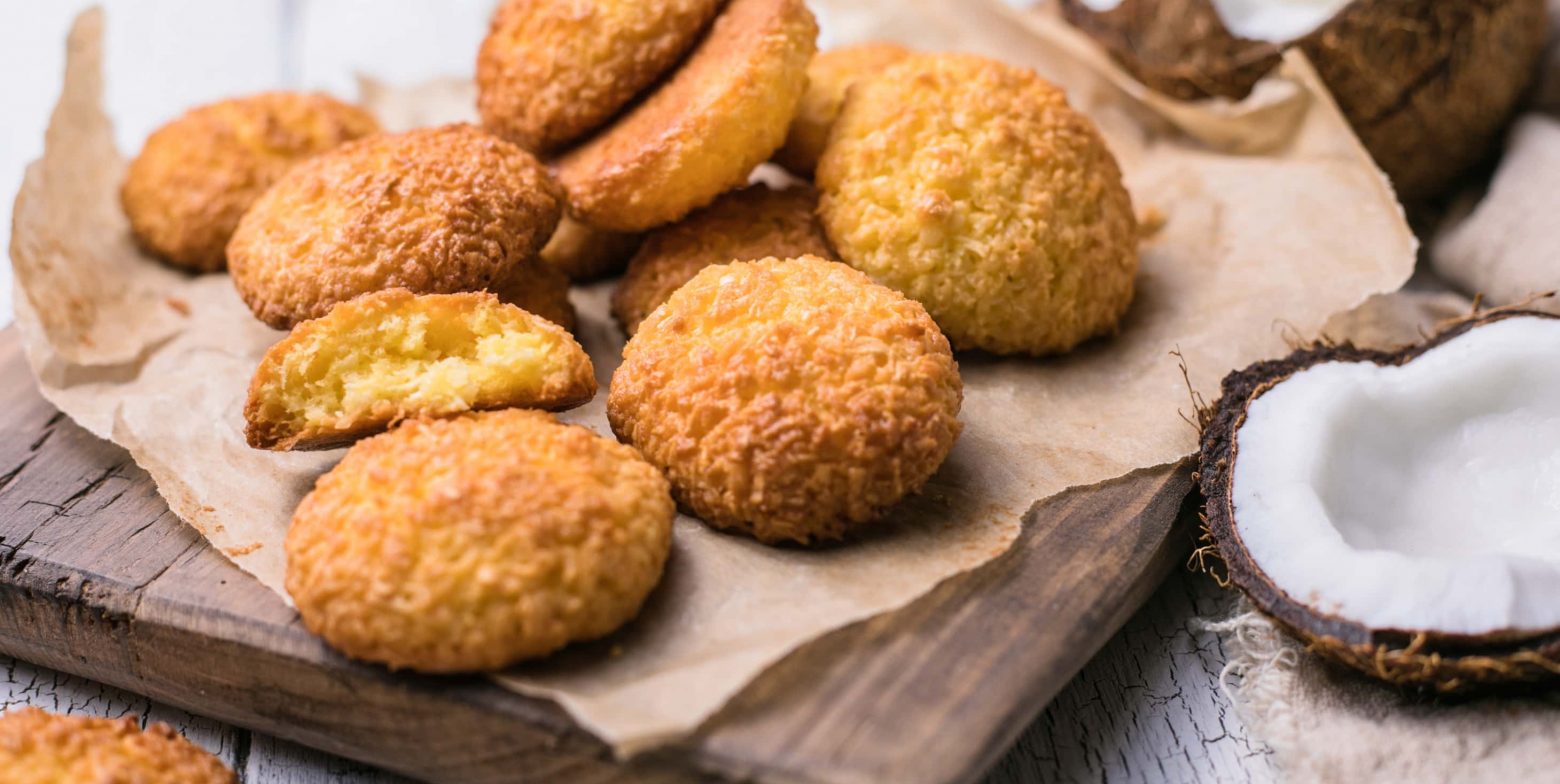 Coconut cookies on parchment paper next to fresh coconut in a shell