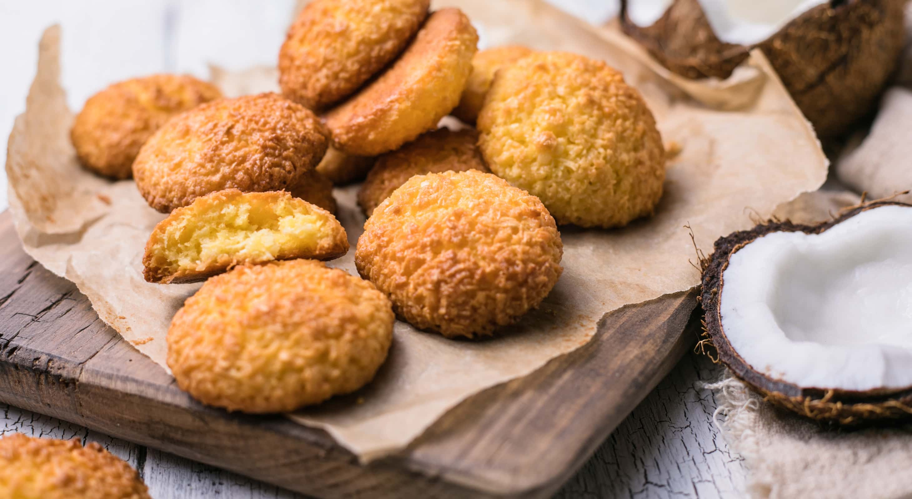 Coconut cookies on parchment paper next to fresh coconut in a shell