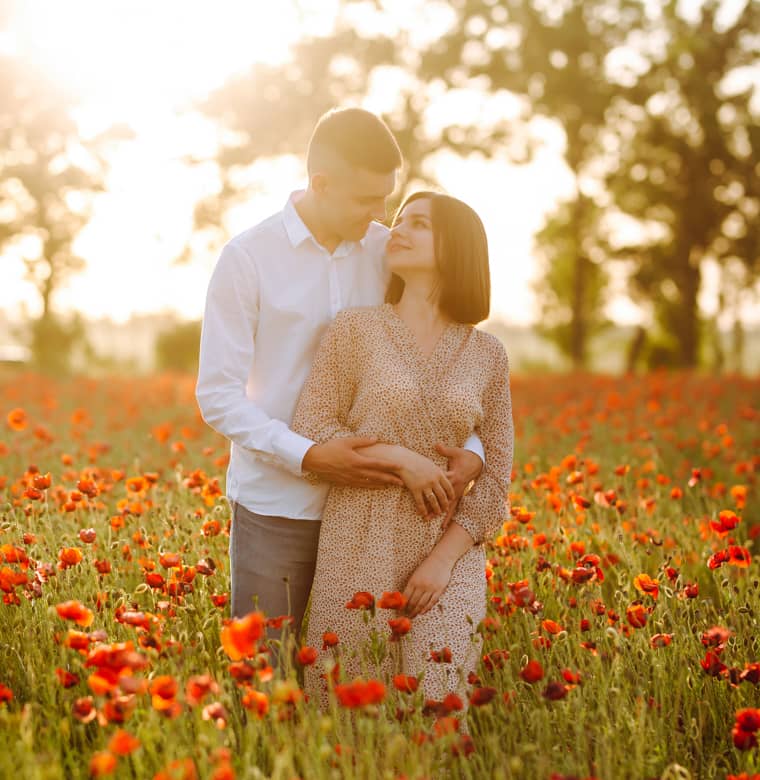 Husband and Wife standing in a field of flowers